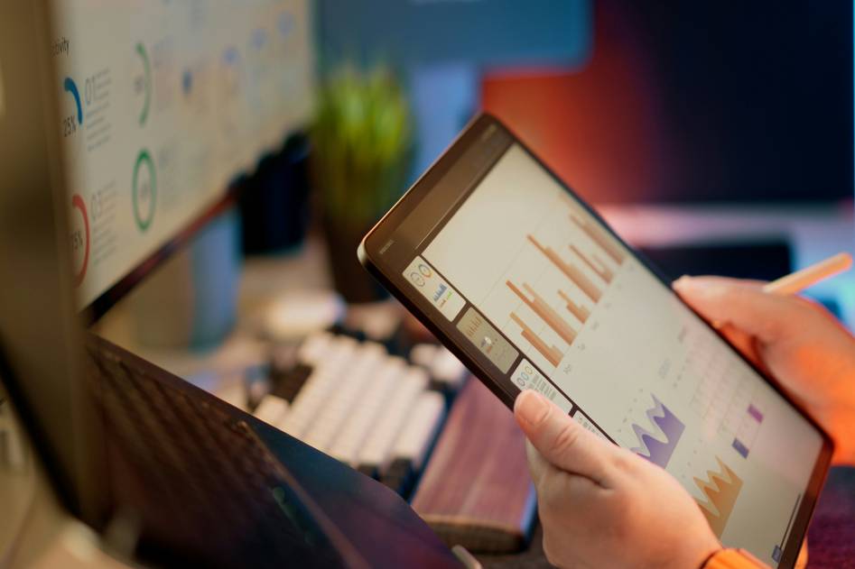 Laptop displaying a paper trading app interface with candlestick charts and portfolio metrics